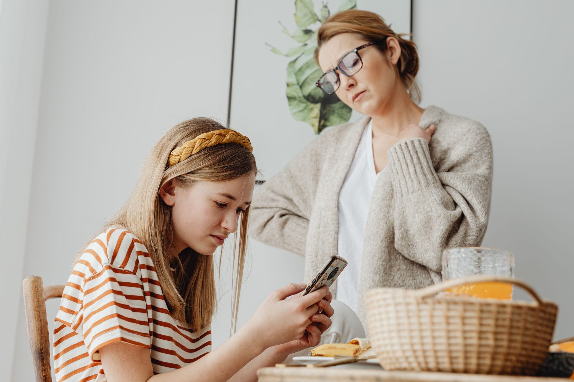 Mama rozmawia z córką zapatrzoną w telefon przy śniadaniu